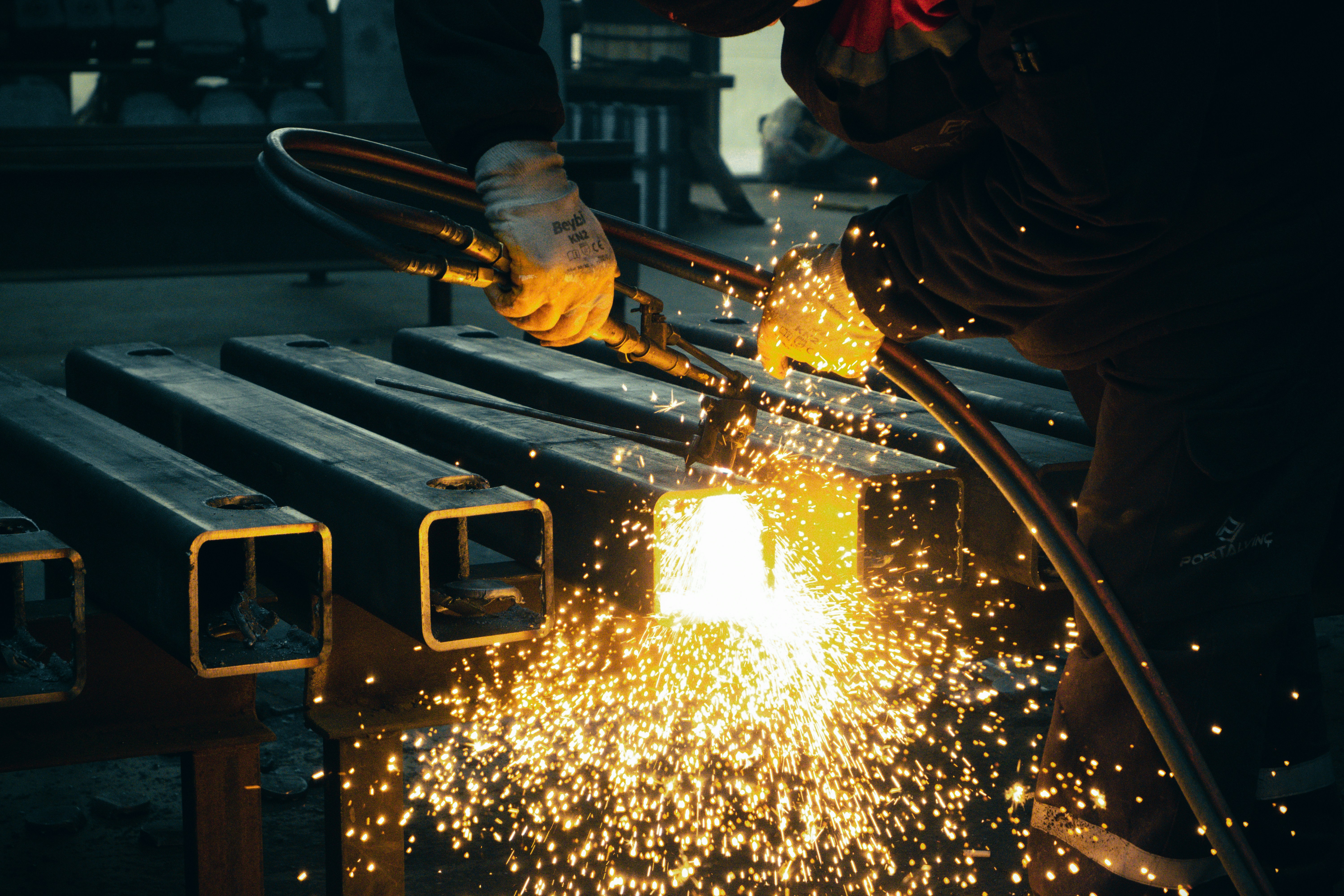 Welder at work with sparks in an industrial fabrication shop